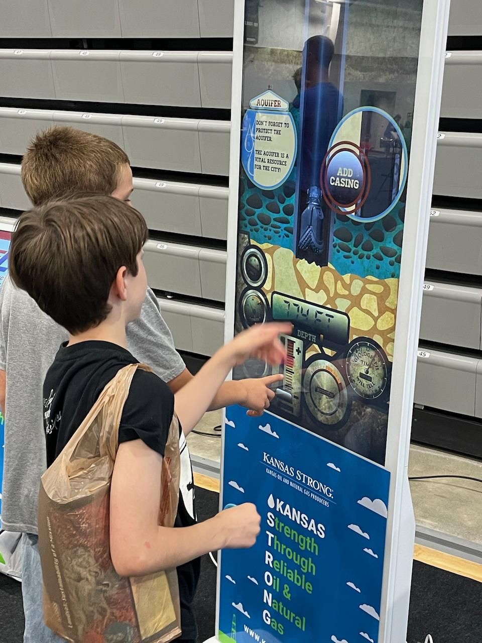Two children standing in front of a Kansas Strong banner.