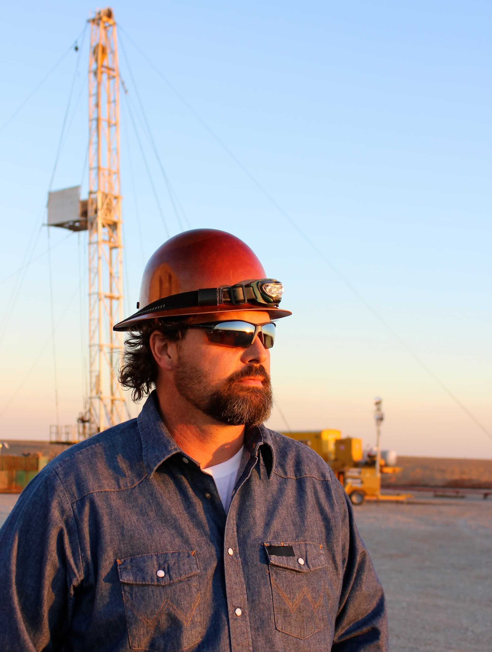 Oil worker with sunglasses and red hardhat.