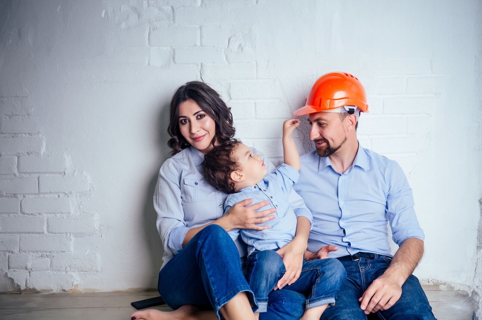 Women holding a child with a man wearing a hardhat sitting next to them.